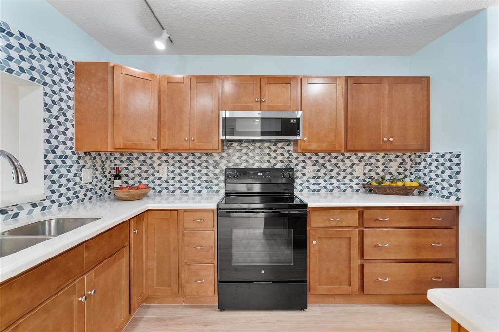 2900 Southwest 22nd Circle, Unit 221E Delray Beach, FL 33445 - Photo 10 of 43 a kitchen with granite countertop a sink and a stove top oven