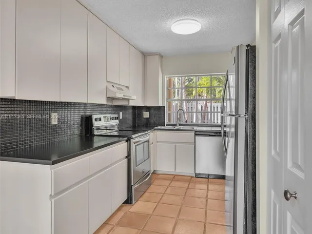 a kitchen with granite countertop a refrigerator and a sink