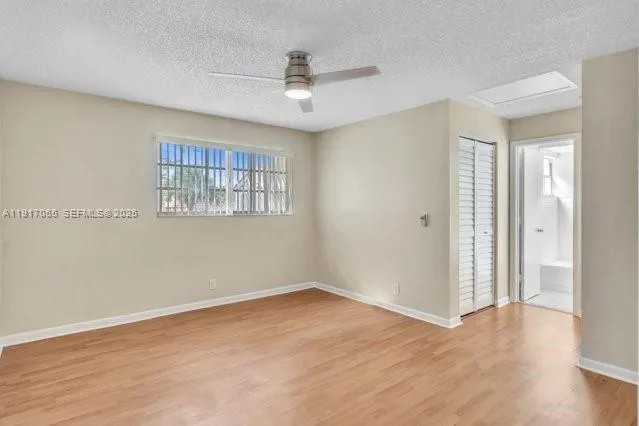 an empty room with wooden floor a ceiling fan and windows