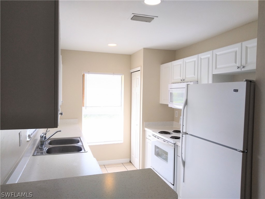 2213 Wilson Road Lehigh Acres, FL 33973 - Photo 2 of 14 a kitchen with stainless steel appliances a refrigerator sink and cabinets