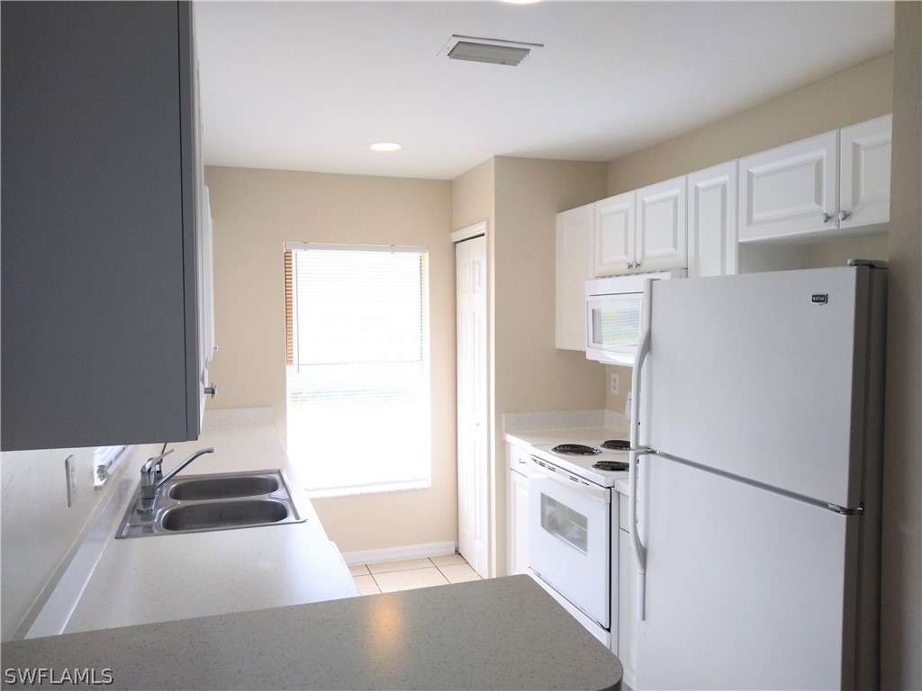 2213 Wilson Road Lehigh Acres, FL 33973 - Photo 5 of 14 a kitchen with a refrigerator a stove a sink and a window