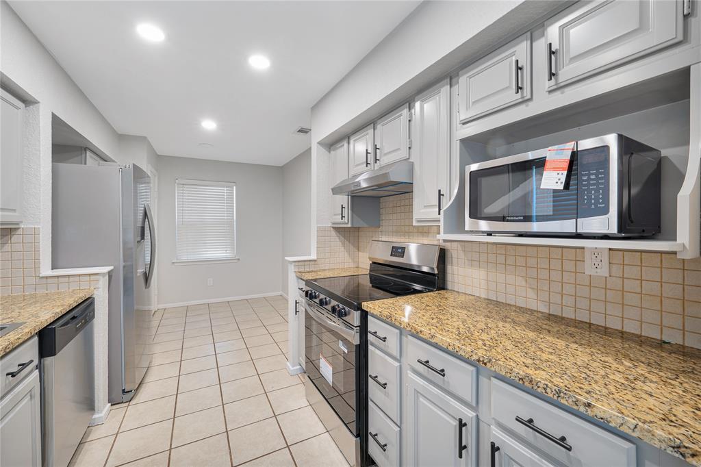 9227 Pinewood Drive Dallas, TX 75243 - Photo 11 of 27 a kitchen with stainless steel appliances granite countertop a stove a sink and a microwave