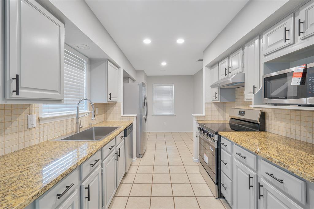 9227 Pinewood Drive Dallas, TX 75243 - Photo 12 of 27 a kitchen with stainless steel appliances granite countertop a sink stove and cabinets