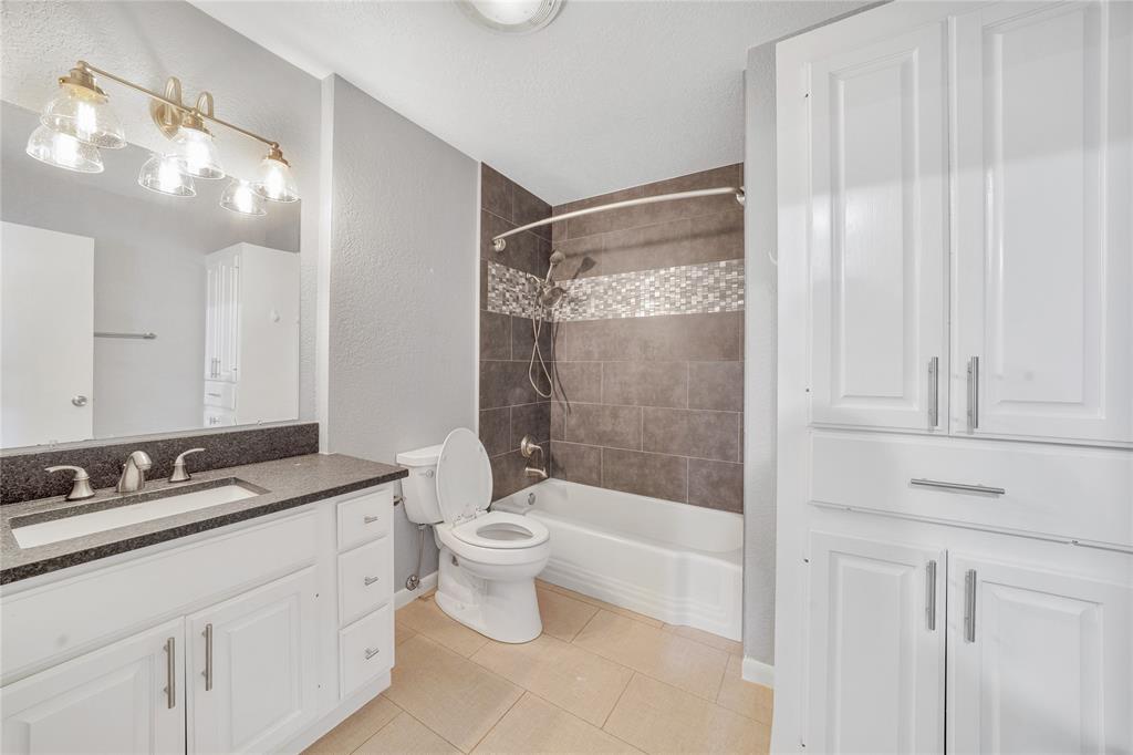 9227 Pinewood Drive Dallas, TX 75243 - Photo 19 of 27 a bathroom with a double vanity sink a toilet a mirror and shower