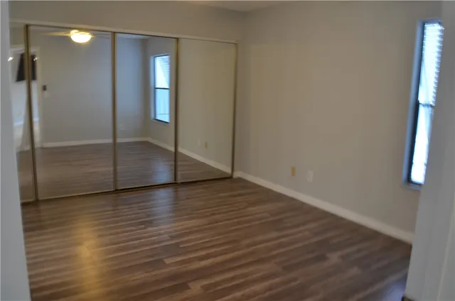 a view of an empty room with wooden floor and a bathroom