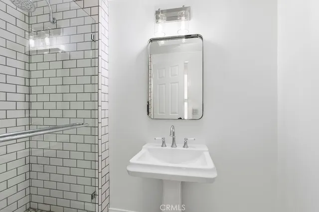 a view of an empty room with wooden floor and a bathroom