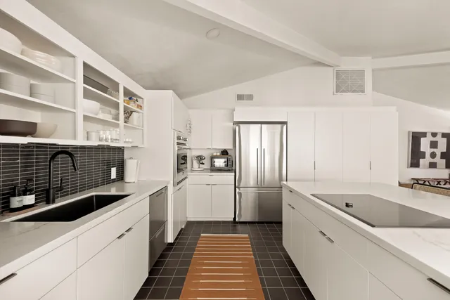 a bed sitting in a bedroom next to a window with a chair