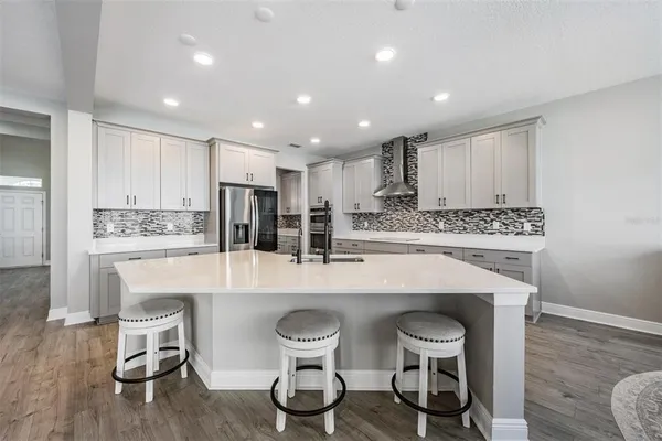 a large white kitchen with wooden floor and chairs