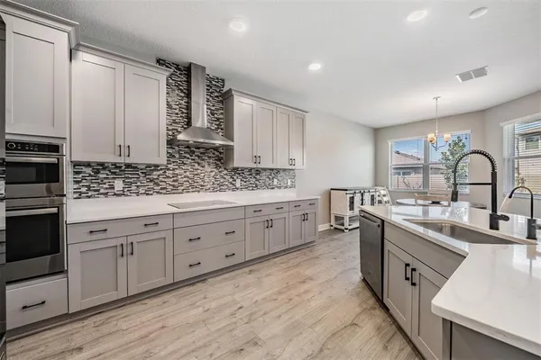 a large white kitchen with a stove a sink a refrigerator and a dining table with wooden floor