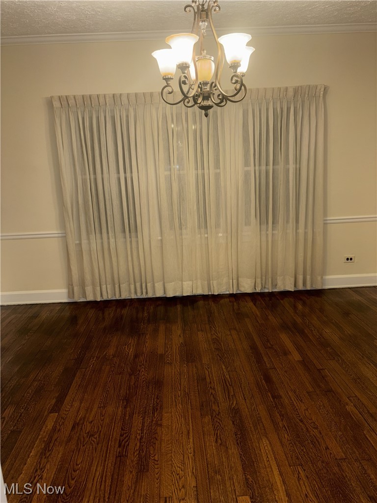 1019 Quilliams Road Cleveland Heights, OH 44121 - Photo 8 of 32 Unfurnished dining area featuring crown molding, a textured ceiling, dark wood-type flooring, and a chandelier