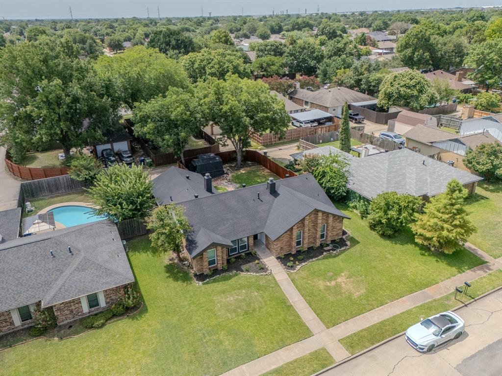 142 Ridgegate Drive Garland, TX 75040 - Photo 3 of 26 Brick exterior residence featuring a dark shingle roof, established landscaping, and a fenced backyard