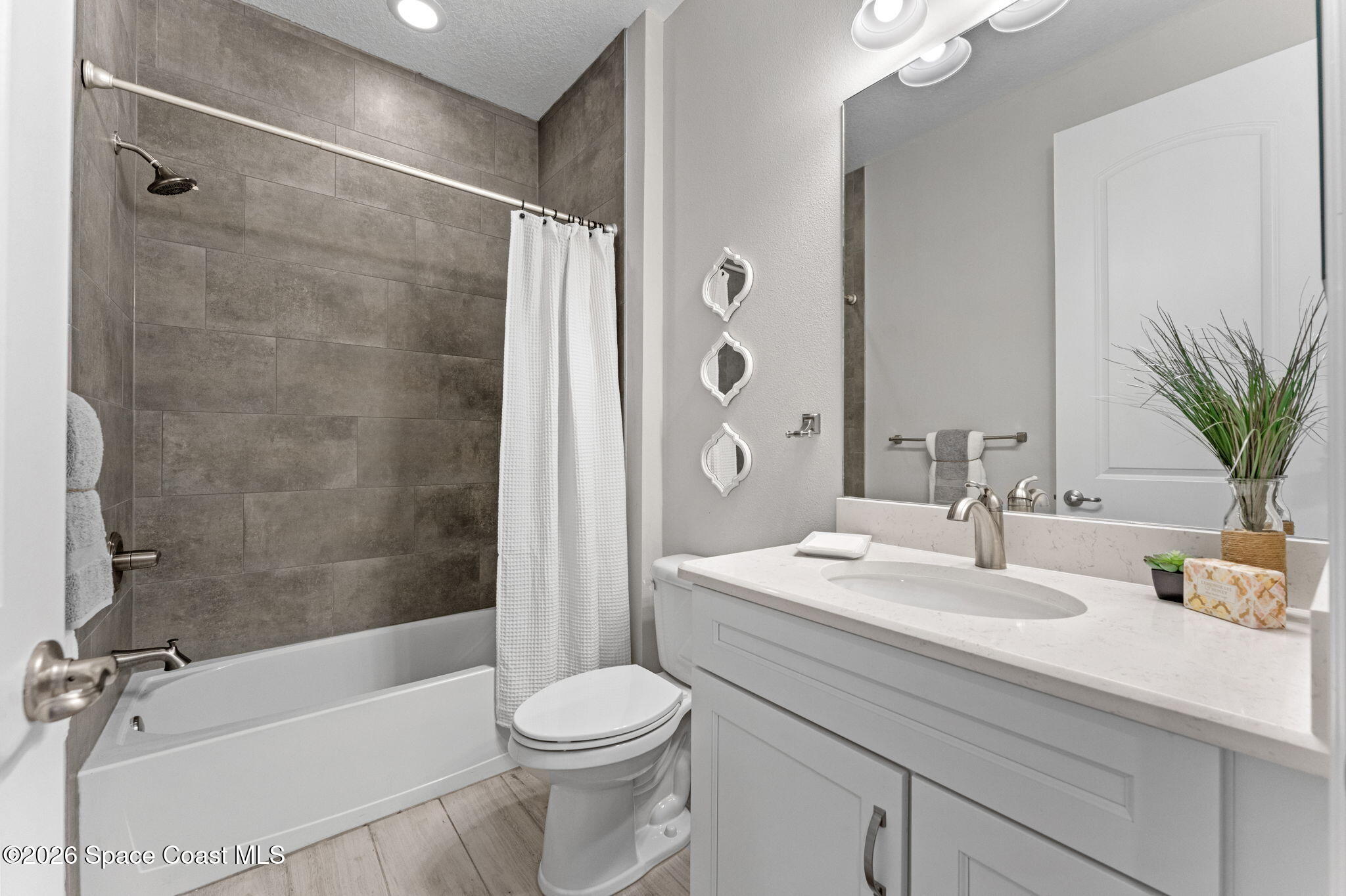 3158 Addison Drive Melbourne, FL 32940 - Photo 28 of 51 a bathroom with a sink a toilet a mirror a bathtub and shower