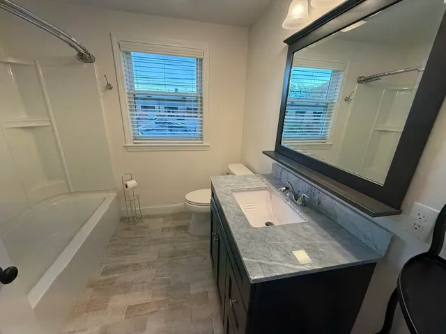 a bathroom with a granite countertop sink a toilet and bathtub