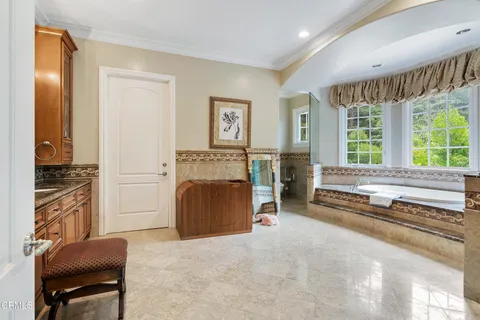 a spacious bedroom with a bed dresser and a large window