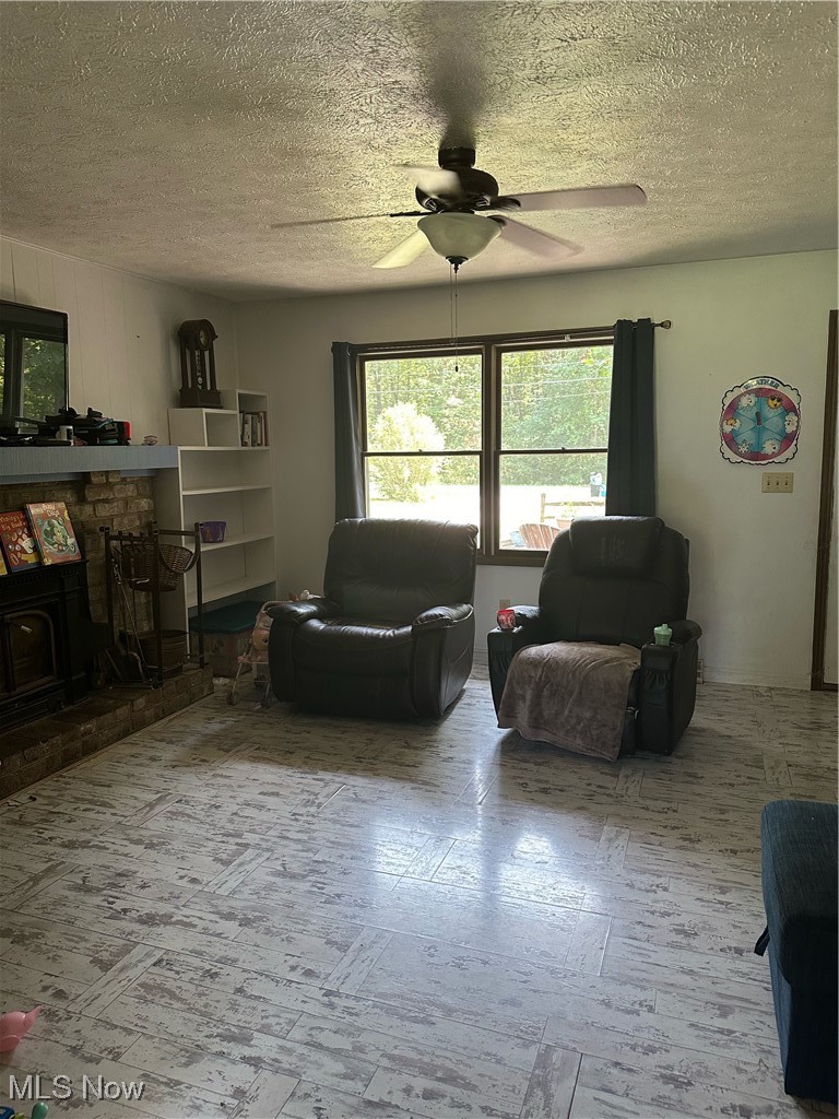 15528 Stoltz Road Diamond, OH 44412 - Photo 9 of 28 Living room with a fireplace, a textured ceiling, and ceiling fan