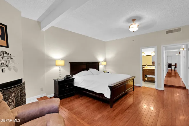 a spacious bedroom with a bed and wooden floor