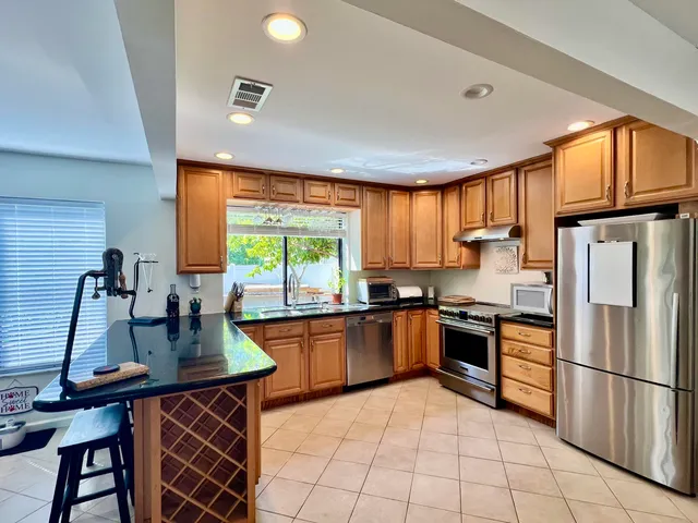 a large kitchen with stainless steel appliances granite countertop a sink and cabinets