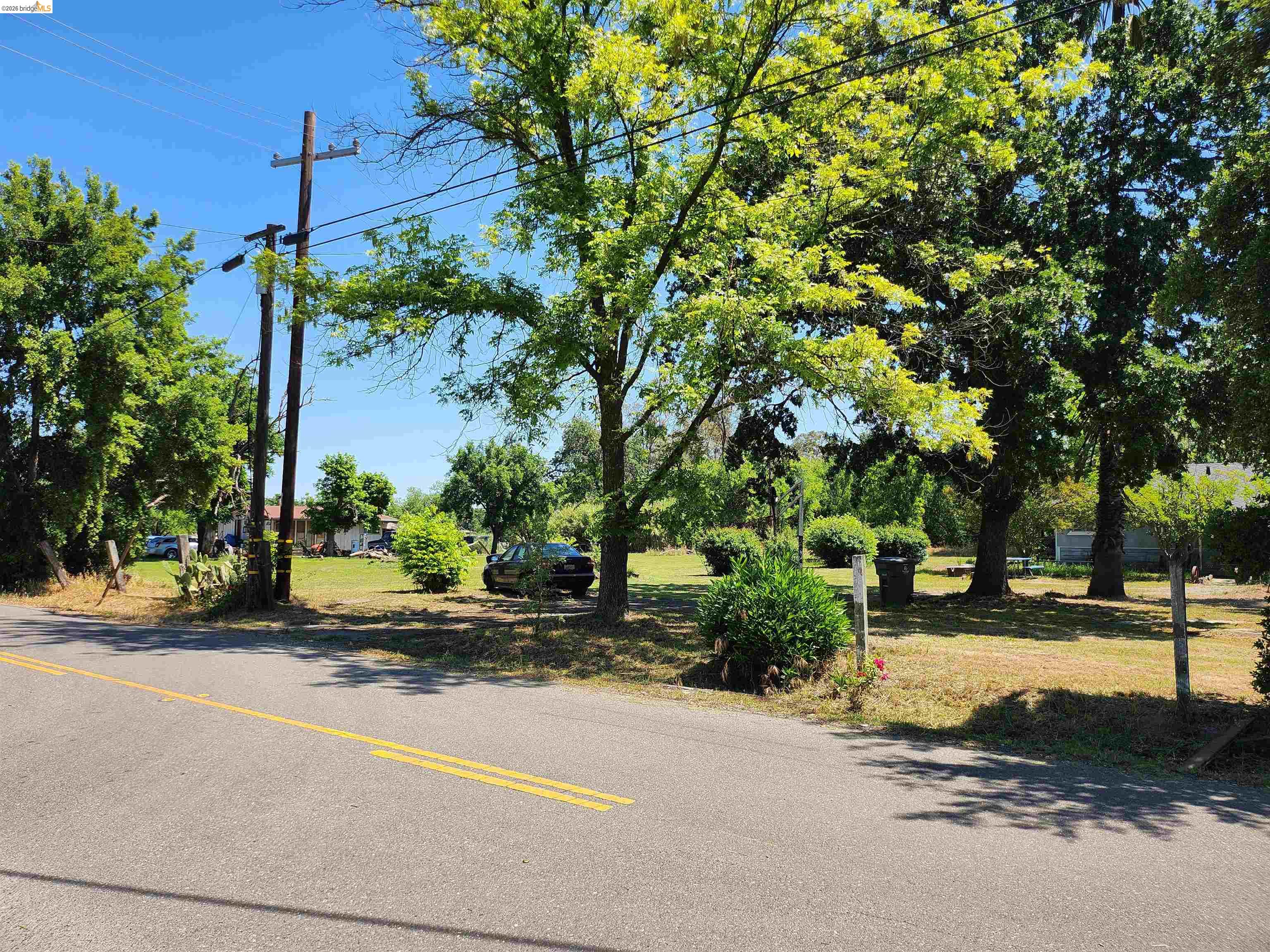 7750 Locke Road Vacaville, CA 95688 - Photo 17 of 23 Expansive parcel featuring mature trees, a flat grassy area, and roadside access