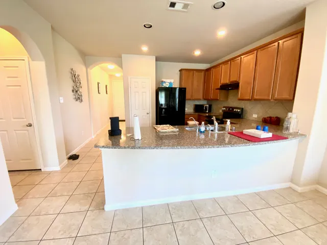 a kitchen with stainless steel appliances a sink a stove a refrigerator cabinets and a dining table with wooden floor