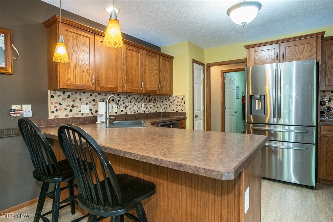 126 Timber Ridge Drive Elyria, OH 44035 - Photo 21 of 49 Kitchen featuring stainless steel fridge with ice dispenser, a sink, tasteful backsplash, a peninsula, and a textured ceiling