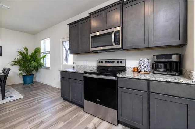 a kitchen with stainless steel appliances granite countertop wooden cabinets a stove top oven a sink and dishwasher