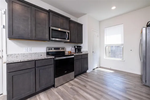 a kitchen with kitchen island granite countertop a sink dishwasher stove and microwave with wooden floor