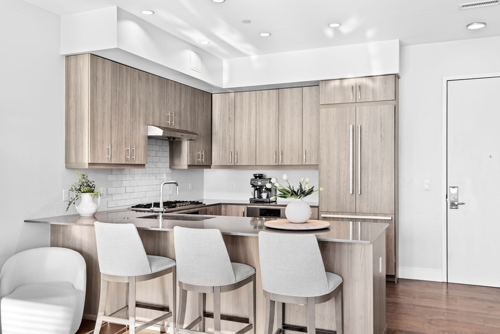 10 Shipyard Drive, Unit 215 Hingham, MA 02043 - Photo 11 of 18 a kitchen with stainless steel appliances a dining table chairs and white cabinets
