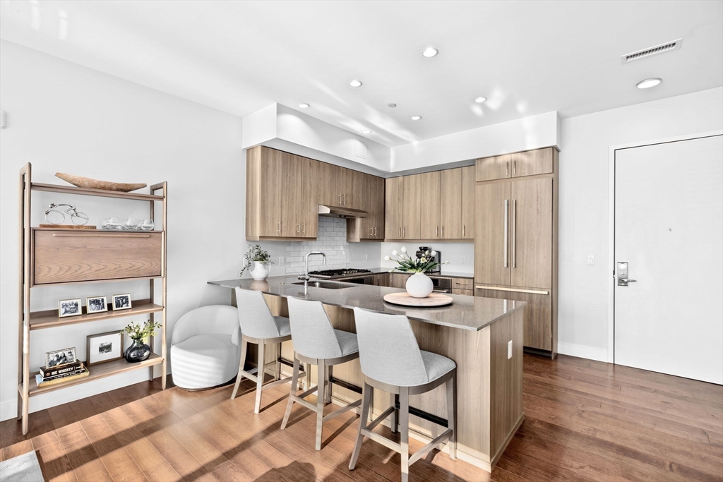 10 Shipyard Drive, Unit 215 Hingham, MA 02043 - Photo 9 of 18 a kitchen with stainless steel appliances granite countertop a stove a refrigerator a microwave a dining table and chairs with wooden floor