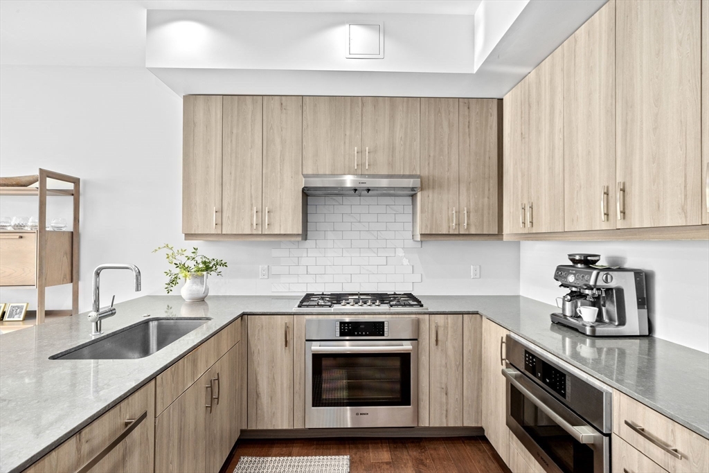 10 Shipyard Drive, Unit 215 Hingham, MA 02043 - Photo 10 of 18 a kitchen with granite countertop white cabinets and white stainless steel appliances