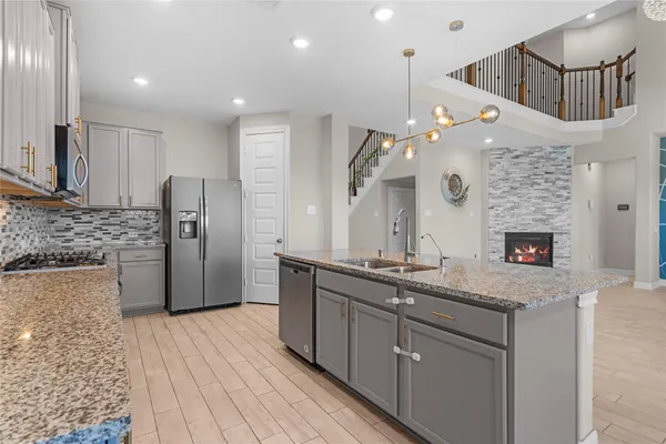 a kitchen with stainless steel appliances granite countertop a sink a oven a refrigerator and a oven with wooden floor