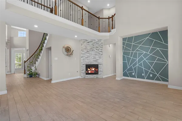 a view of an empty room with wooden floor a fireplace and windows