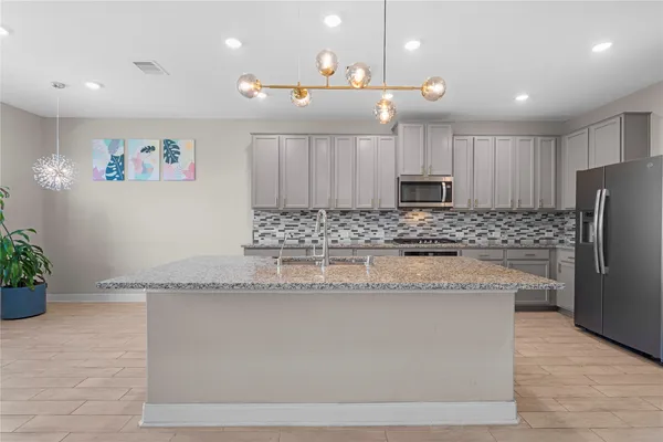 a kitchen with granite countertop a refrigerator a sink and a stove