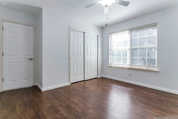 a view of an empty room with wooden floor and a window
