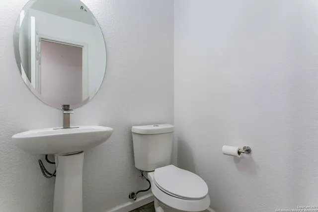 a bathroom with a toilet a sink and mirror