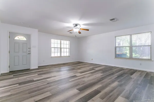 a view of empty room with wooden floor and fan