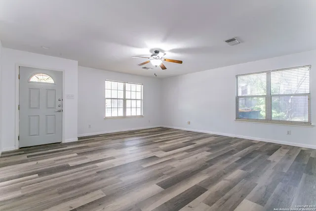 a view of empty room with wooden floor and fan