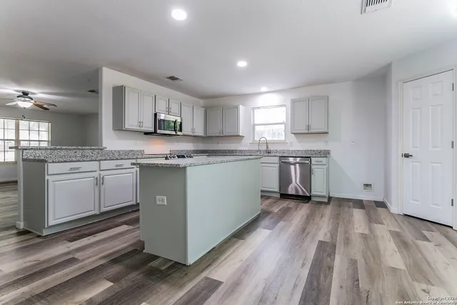 a kitchen with stainless steel appliances granite countertop wooden cabinets and a sink