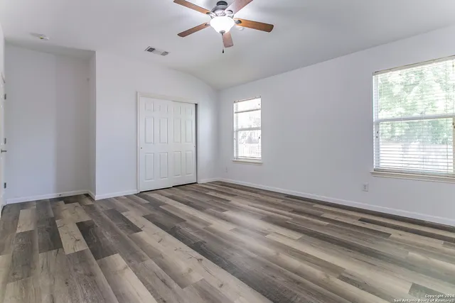 a view of empty room with window and ceiling fan