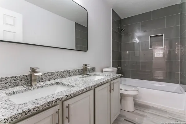 a bathroom with a granite countertop sink a toilet and bathtub