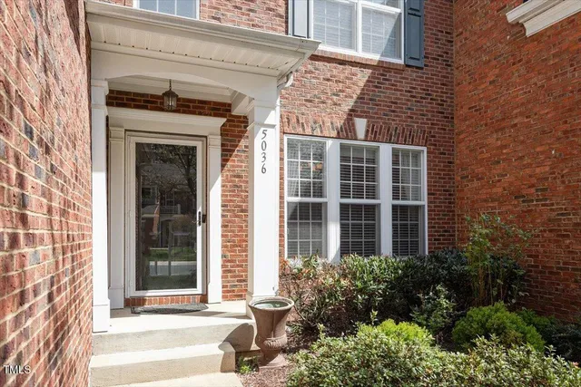front view of a brick house with a large window and potted plants