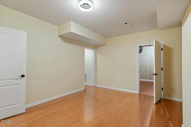an empty room with wooden floor and a bathroom