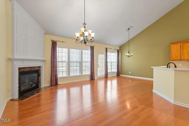 a view of a livingroom with a fireplace wooden floor and chandelier