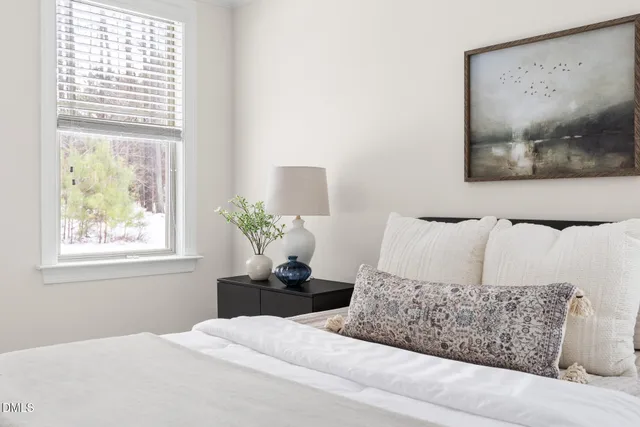 a bedroom with a bed painting on wall and a large window