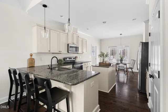 a large kitchen with kitchen island granite countertop a table chairs sink and refrigerator
