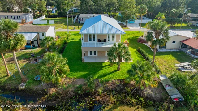 a aerial view of a house with swimming pool and large trees