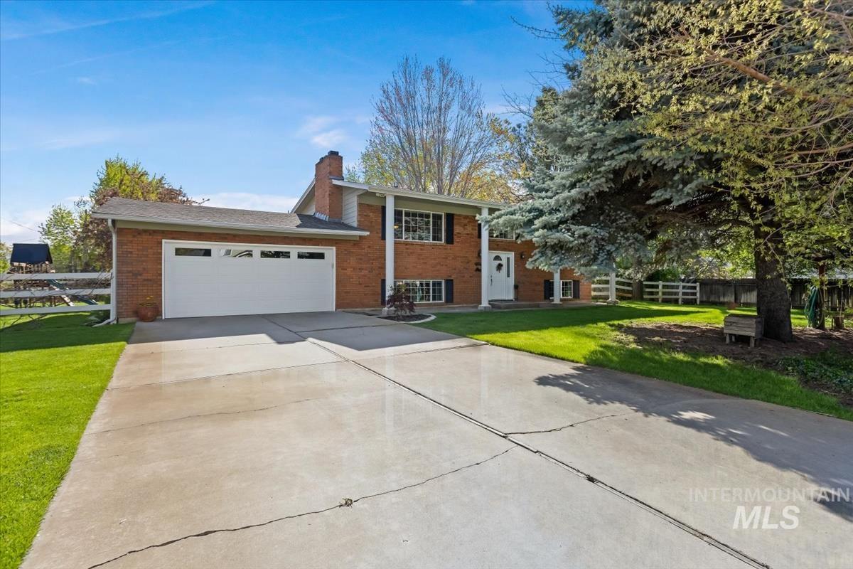 Split foyer home with a garage, brick siding, driveway, and a chimney
