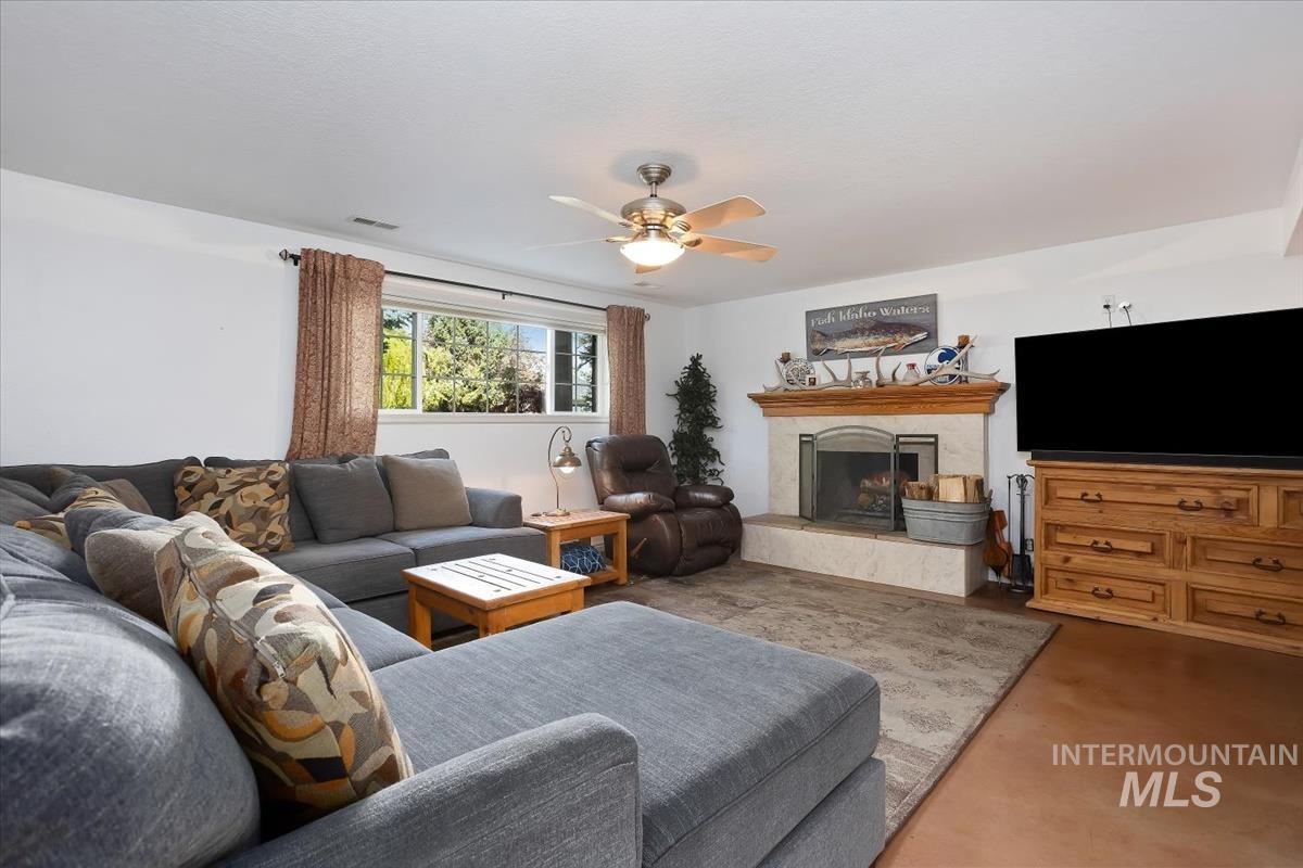4870 North Farrow Street Boise, ID 83713 - Photo 18 of 40 Living room featuring a fireplace, ceiling fan, and finished concrete floors