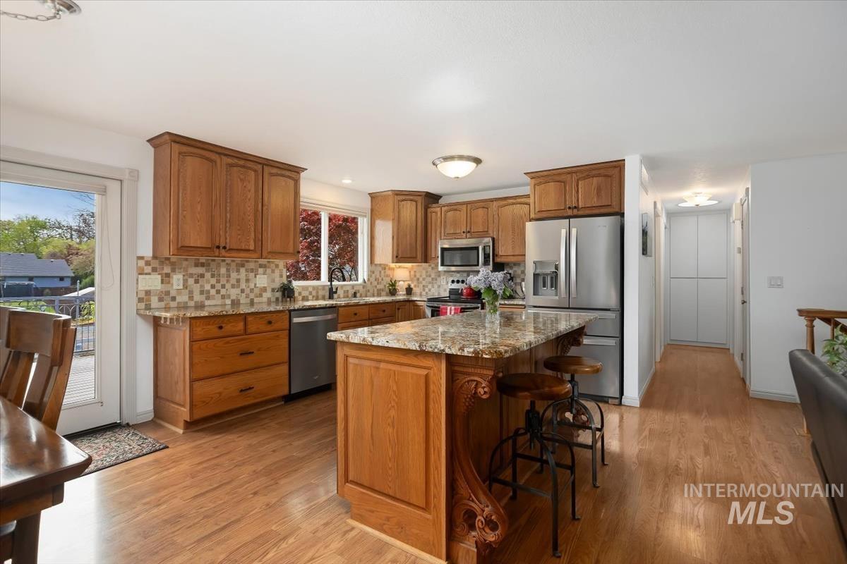 4870 North Farrow Street Boise, ID 83713 - Photo 8 of 40 Kitchen featuring stainless steel appliances, wood finish cabinetry, light stone countertops, and a kitchen breakfast bar