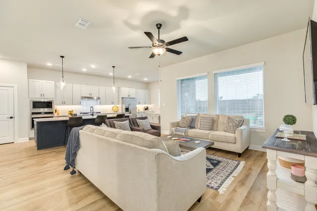 a living room with furniture kitchen view and a chandelier
