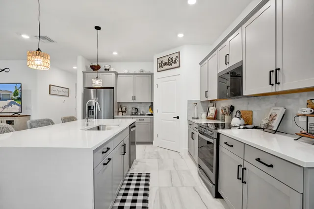 a kitchen with granite countertop a sink a counter space appliances and cabinets